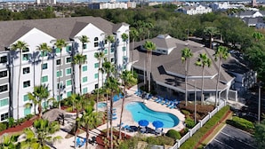 A hotel with a swimming pool, multiple floors, and palm trees. - Disney Epic 1st Floor Shuttle (Orlando)