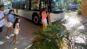A bus with a 'SCHEDULE' sign, parked under a covered area with a tiled floor and potted plants. - Disney Epic 1st Floor Shuttle (Orlando)
