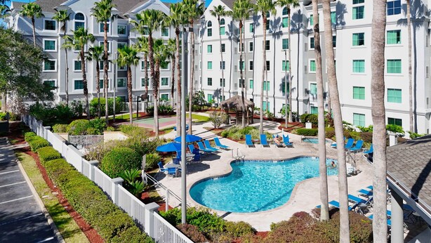 A resort with multiple-story buildings, a central swimming pool, and palm trees. - Disney Epic 1st Floor Shuttle (Orlando)