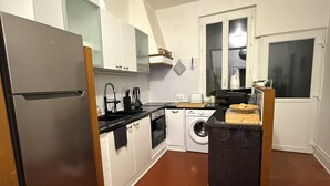 Een praktische keuken met een koelkast, oven, wasmachine en een klein aanrecht.