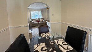 A hallway leading to a living area with a sofa and a glass table with placemats.
