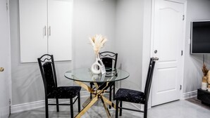 A dining area with a glass table, black chairs, and a white cabinet. - SAINT SUITES EXECUTIVE STAY 2B + 1B (Brampton)