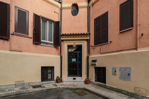 A building with a central entrance, two potted plants, and a small courtyard.