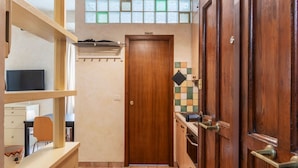 Cuina compacta amb una porta de fusta amb la inscripció 'TOILET', un rebedor d'azulejos i una finestra sobre la porta.