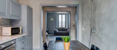 A modern kitchen with grey cabinets, a microwave, and a dining table with a plant.
