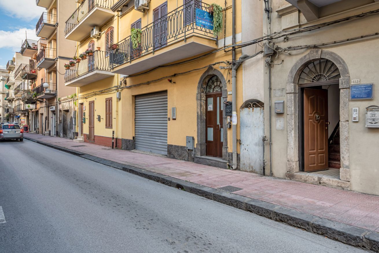 A street with yellow buildings, a closed garage door, and a brown door with a sign.