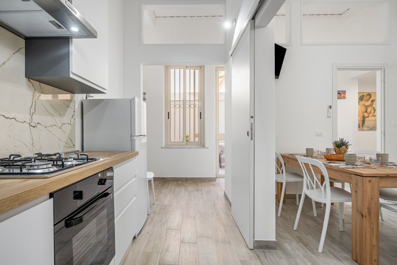 Cozinha moderna com fogão a gás, forno e armários brancos.