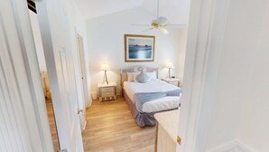 A bedroom with a bed, bedside tables, a ceiling fan, and a framed picture on the wall.