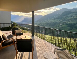 Een balkon met uitzicht op glooiende heuvels en een verre skyline.
