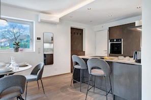 A modern kitchen with a dining area, bar stools, and a view of the outdoors.