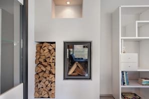A room with a fireplace, a bookshelf, and a window with a view of the outdoors.