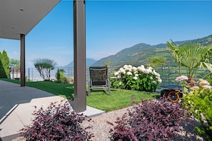 Un espace extérieur moderne offrant une vue sur les montagnes, un jardin avec différentes espèces de plantes et un coin salon.