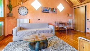 A cozy room with a wooden ceiling, a clock, a cactus, a dining table with chairs, and a sofa.