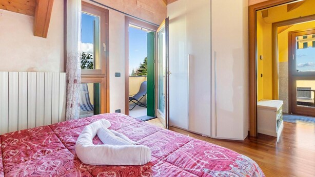 A bedroom with a bed, a white wardrobe, and a sliding glass door leading to a balcony.