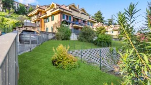 A residential building with a well-maintained lawn, a stone wall, and a metal fence.