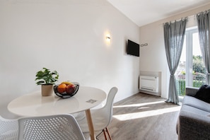 A modern living room with a round table, white chairs, a grey sofa, a potted plant, and a fruit bowl. - Apartment 'Garda Flow' with Wi-Fi and Air Conditioning (Lonato del Garda)