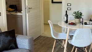 Un espacio habitable compacto con comedor, kitchenette y un sofá con cojín negro.