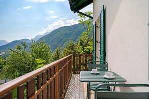 Un balcone con ringhiera in legno, un tavolo e una sedia.