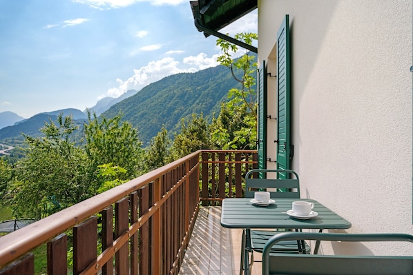 A balcony with a wooden railing, a table, and a chair.