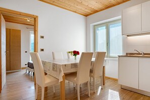 Une cuisine moderne avec des meubles blancs, un plafond en bois et un coin repas comprenant une table et des chaises.