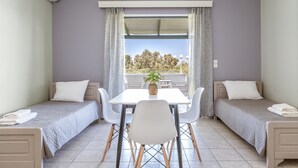 A room with two single beds, a dining table with chairs, a window with curtains, and an air conditioning unit. - Studio Apartment '1' with Private Terrace, Wi-Fi and Air Conditioning (Kalón Nerón)