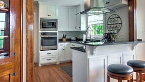 Une cuisine moderne avec des meubles blancs, des appareils en acier inoxydable et un îlot central doté de tabourets.