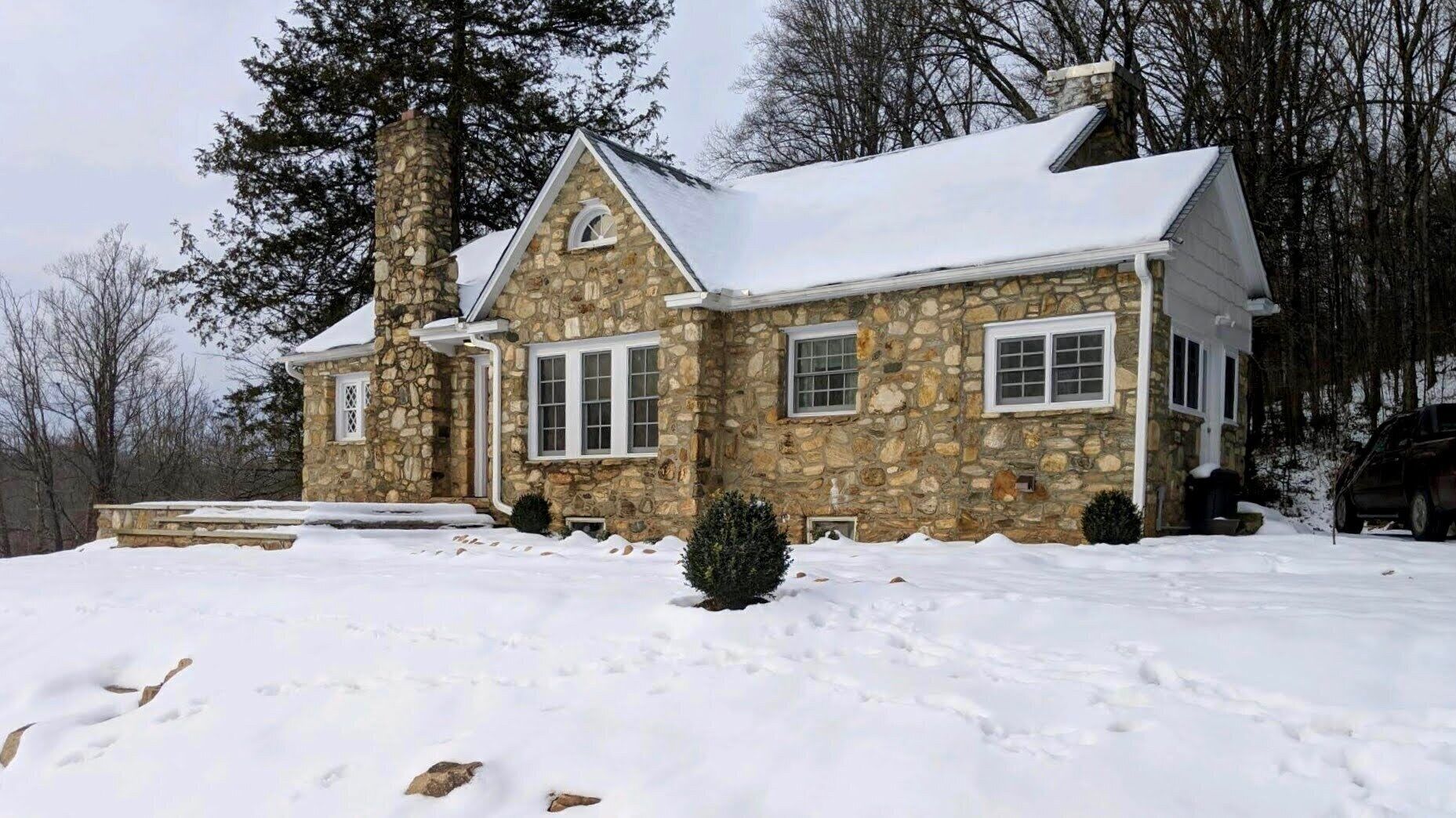 A stone house with a snow-covered roof and a chimney.