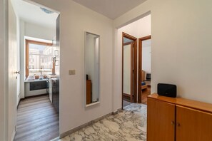 A hallway with a kitchen, a mirror, and a wooden cabinet.