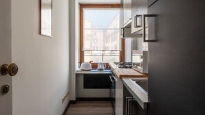 Eine schmale Küche mit Fenster, Wasserkocher, Mikrowelle und Herd.