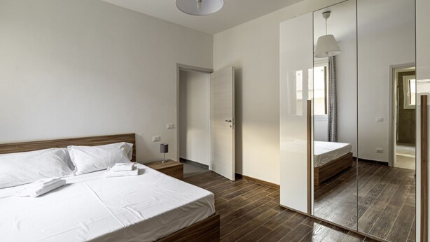 A bedroom with a bed, bedside table, and a wardrobe with a mirror.