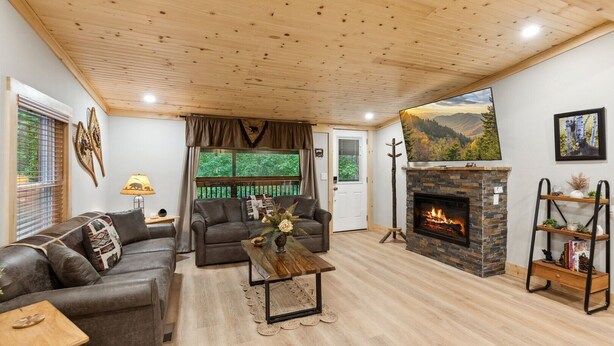 A cozy living room with a fireplace, leather sofas, and a wooden ceiling.