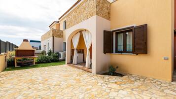 Una casa con patio in pietra, zona salotto esterna e ingresso coperto.