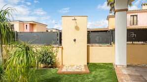 A courtyard with a small lawn, a water feature, and a building with a tiled roof. - Holiday Home 'Giardino' with Private Garden, Wi-Fi and Air Conditioning (Villasimius)