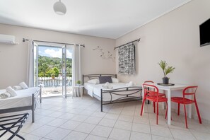 Ein Hotelzimmer mit Bett, einem kleinen Tisch mit Stühlen, einem Balkon mit Blick und einem an der Wand befestigten Fernseher.