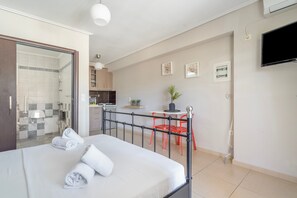 A bedroom with a bed, a bathroom, a kitchenette, and a dining area with a table and chairs. - Apartment 'Alexandros Amea' with Mountain View, Wi-Fi and Air Conditioning (Lefkada Town)