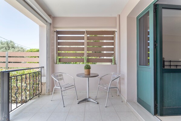 A balcony with a table and two chairs, a potted plant, and a sliding door.