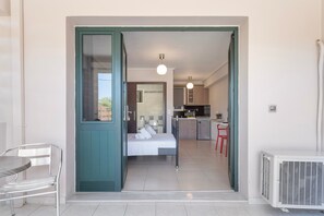 A room with a bed, a small kitchenette, a dining area with a table and chairs, and a view through an open door. - Apartment 'Alexandros Amea' with Mountain View, Wi-Fi and Air Conditioning (Lefkada Town)