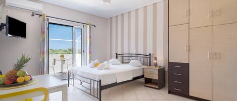 A bedroom with a bed, bedside table, wardrobe, and a view through a window.