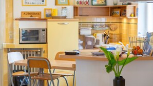 A kitchen with a microwave, a refrigerator, and a dining area with chairs and a table.