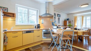 A kitchen with yellow cabinets, a stove, and a dining area with chairs and a table.