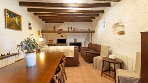 A rustic interior with exposed wooden beams, a dining area with a table and chairs, a sofa, and a television. - Country House 'Emilli' with Mountain View, Wi-Fi and Air Conditioning (Unknown)