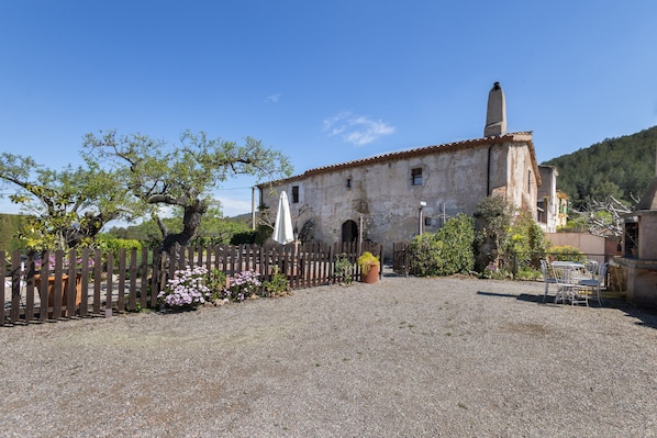 A rustic building with a stone facade, a wooden fence, and a gravel courtyard.