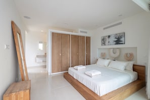 A modern bedroom with a large bed, wooden wardrobe, and a minimalist design.