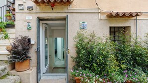 A building entrance with a door, potted plants, and a small window. - Apartment 'CasaMia Civico14 - Turchese' with Wi-Fi and Air Conditioning (Salerno)