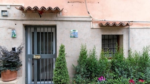 A building with a stone facade, a metal gate, potted plants, and a small window.