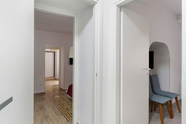 Un pasillo con una silla, una lámpara y un televisor en la pared.