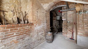 An arched brick corridor with a barrel, a broom, and a bucket. - Holiday Home 'Dello Zio Birba' with Balcony and Wi-Fi (Portacomaro)