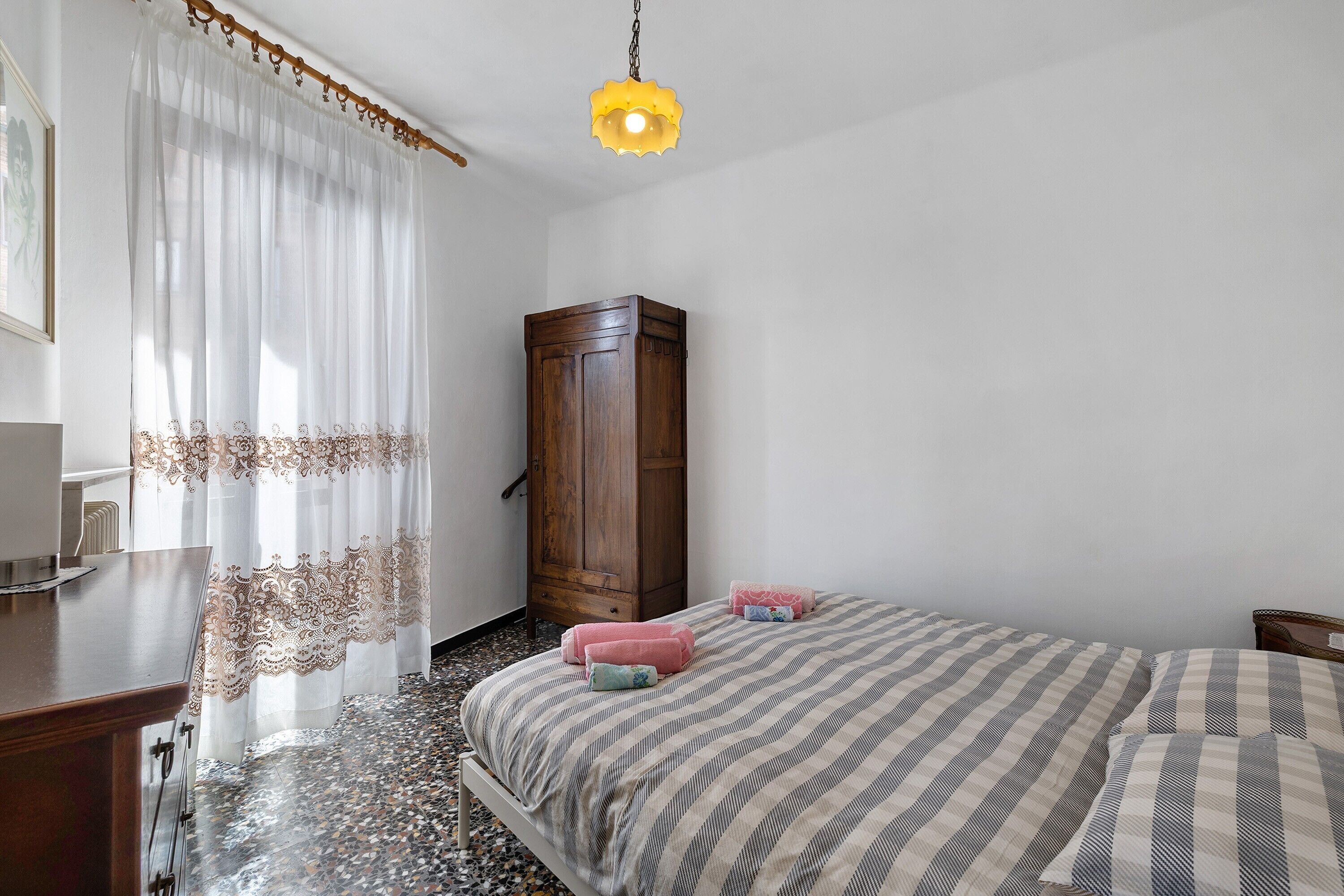 Una camera da letto con un letto, un'armadietto in legno, una scrivania e un lampadario.
