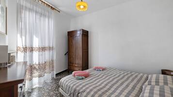 Una camera da letto con un letto, un'armadietto in legno, una scrivania e un lampadario.