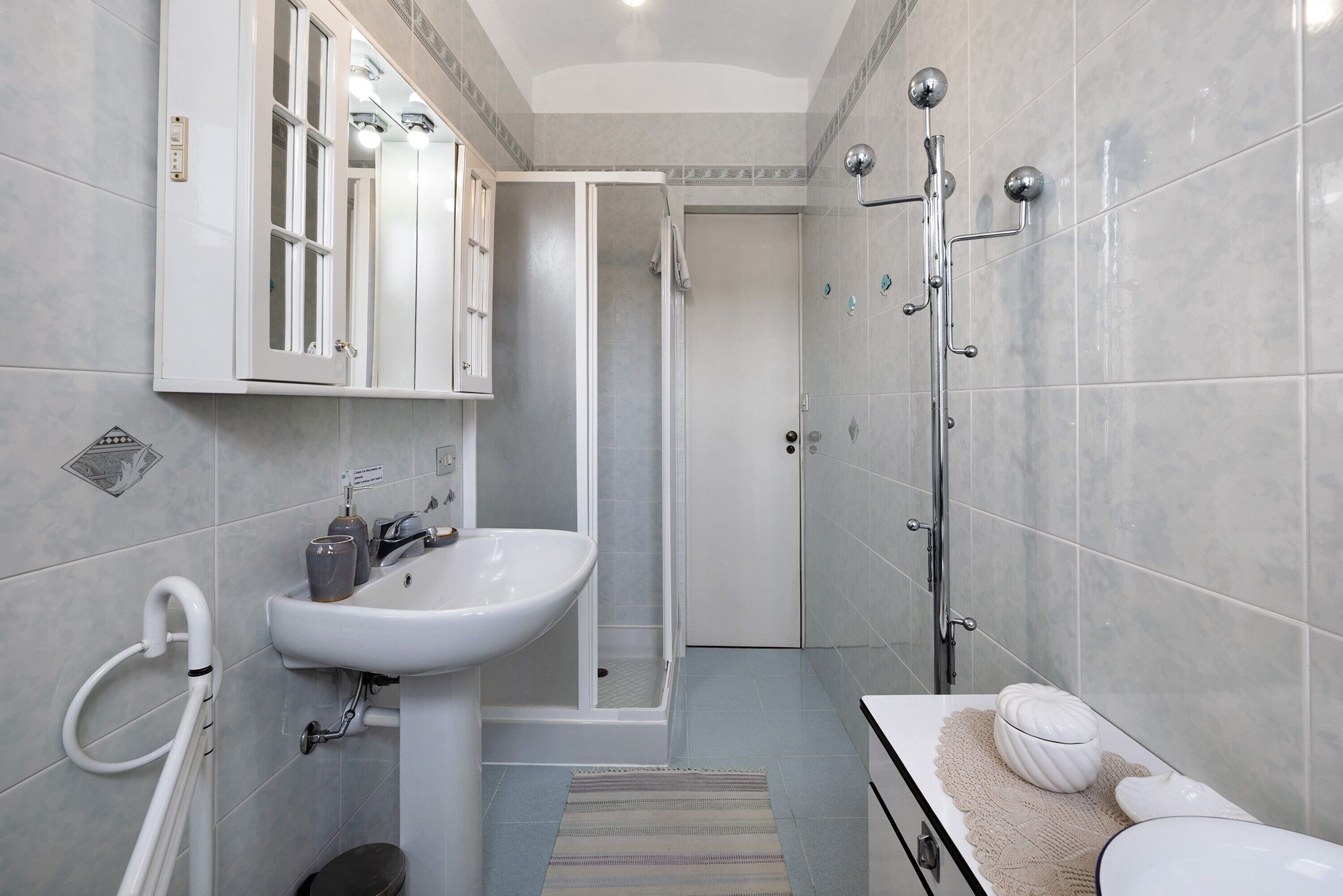 Une salle de bain moderne équipée d’un lavabo, d’un miroir, d’une douche et de toilettes.